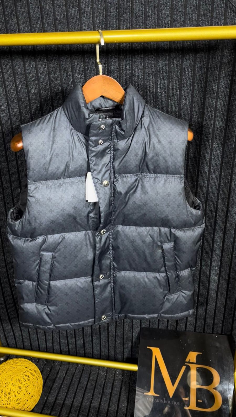 Grey cross-print down vest on a hanger